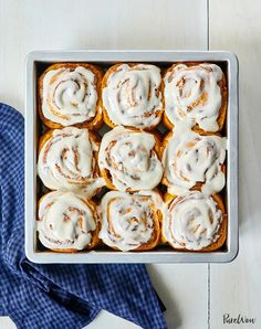 a pan filled with cinnamon rolls covered in icing