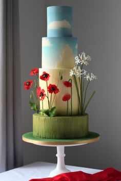 a three tiered cake decorated with flowers and grass