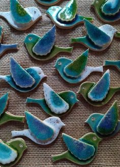 decorated cookies with blue, green and white birds on a brown tableclothed surface