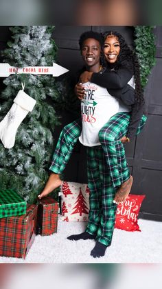 two people standing in front of a christmas tree