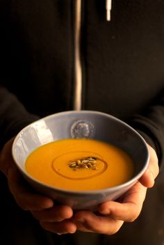 a person holding a bowl of soup in their hands