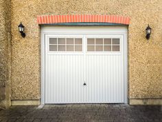 a white garage door is open in front of a stucco wall and brick flooring