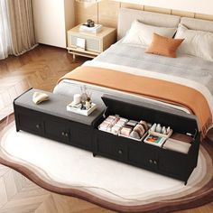 a bed with drawers underneath it in a bedroom next to a table and lamp on the floor