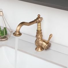 a faucet that is on top of a sink next to a potted plant