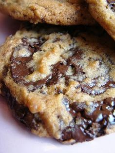 three chocolate chip cookies stacked on top of each other in front of a white plate