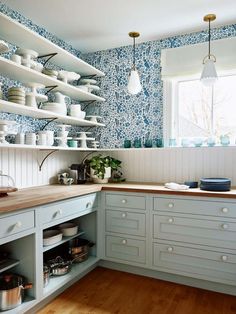 a kitchen with blue and white wallpaper, wooden flooring and open shelving