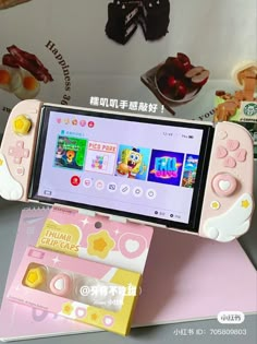 a pink and white game controller sitting on top of a table next to other items