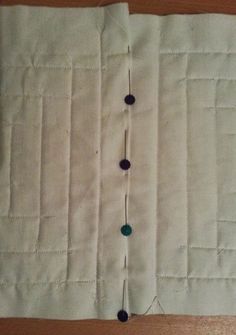 a close up of a piece of cloth on a wooden table with buttons and thread