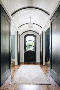 an entry way with black doors and a rug on the floor