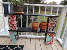 some pots are sitting on a shelf on the porch near a potted planter