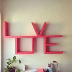 the word love is spelled in pink letters above a desk with a computer and potted plant