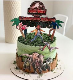 there is a cake with dinosaurs and people on it that says jumbo world adventure park