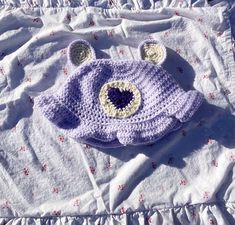 a crocheted bear hat laying on top of a bed