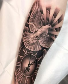 a clock and bird tattoo on the arm