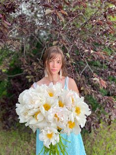 a woman holding a bouquet of white and yellow flowers