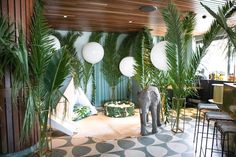 an elephant is standing in the middle of a room with palm trees and white balloons