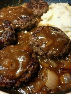 some meatballs and potatoes are in a skillet with gravy on the side