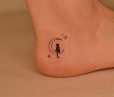 a black cat sitting on the moon with stars around its neck tattooing it's foot