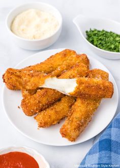 some fried food on a white plate with sauces and seasoning next to it