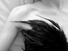 a black and white photo of a woman with feathers on her chest