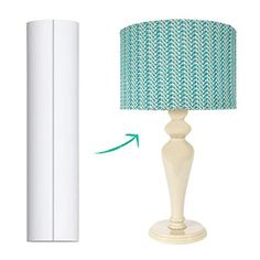 a white lamp with a green fabric shade next to a tall white paper tube on a white background