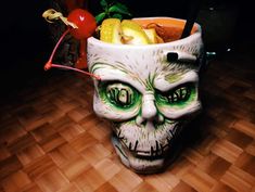 a skull - shaped drink cup with green eyes and mouth painted on it's side