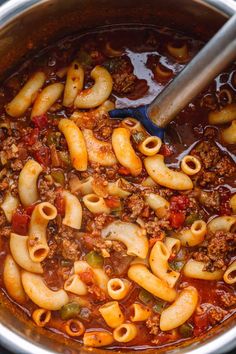 a pot full of pasta and meat sauce with a ladle scooping in it