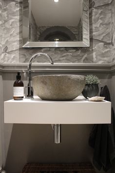 a bathroom sink sitting under a mirror in front of a wall mounted faucet