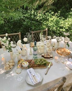 an outdoor table set with food and wine