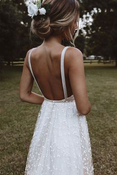 the back of a woman's dress with flowers in her hair, standing on grass