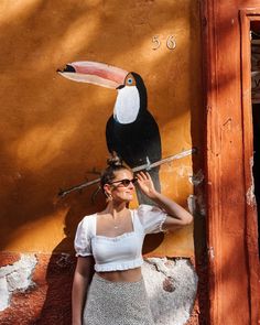 a woman standing in front of a wall with a toucan painted on it