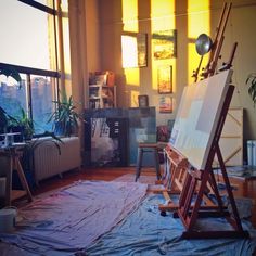 an artist's easel sitting on top of a blue tarp in front of a window