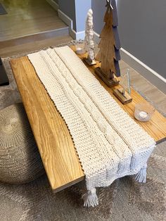 a knitted table runner sitting on top of a wooden floor next to a christmas tree