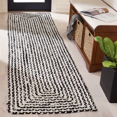 a large black and white rug on the floor in front of a window with a potted plant next to it