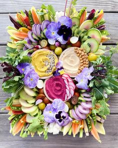 an arrangement of fruits and vegetables arranged in a circle on top of a wooden table