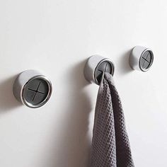 the towel is hanging on the wall next to two hooks with towels in them and one hook has a button that says kaying