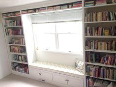 a window seat in front of a book shelf filled with books