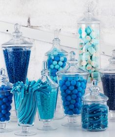 there are many blue and white candies in glass jars