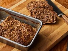 meatloaf in a pan on a cutting board next to a knife and fork