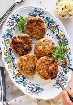 four crab cakes on a plate with a fork and bowl of coleslaw next to it