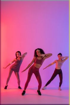 three young women are dancing in front of a pink background