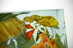 a close up of a glass with flowers and plants in it on a white background