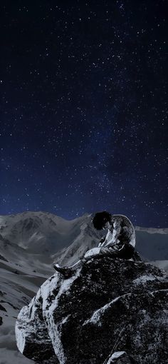 the night sky is filled with stars above some snow covered mountains and rocks in the foreground