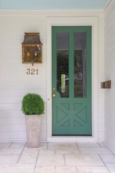 a green front door with a potted plant next to it