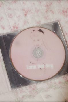 the cd is in its plastic case on the tableclothed surface with pink flowers