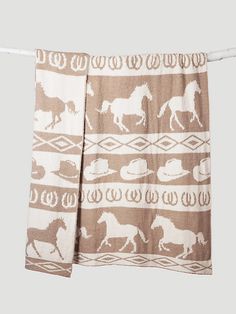 a brown and white towel hanging on a clothes line with horses in the desert pattern