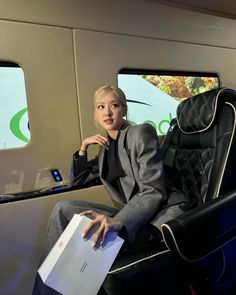 a woman sitting in an airplane seat holding a piece of paper