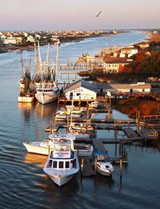 several boats are docked in the water near some houses and buildings on the other side of the river