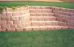 a stone retaining wall with grass in the foreground