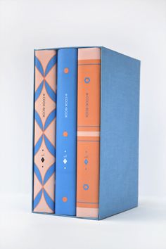 three books are stacked on top of each other, one is blue and the other is orange